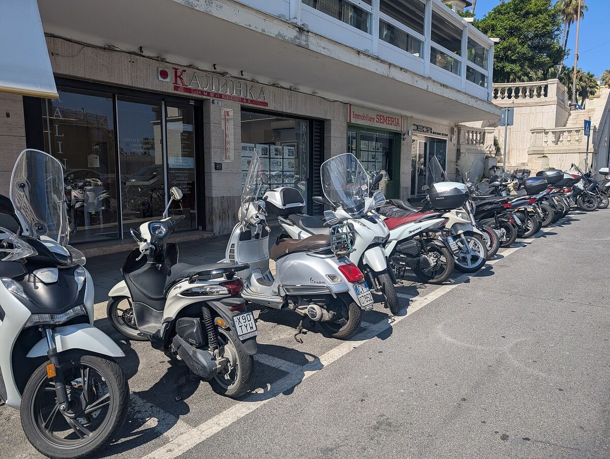 Rangée de scooters et de motos garés le long d'un trottoir dans une rue italienne